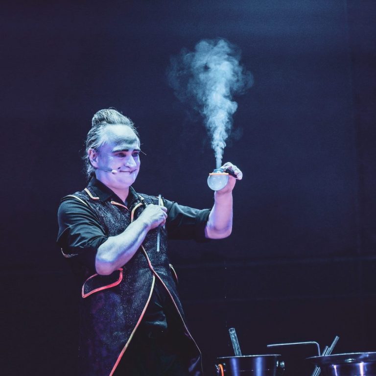 Spectacle de bulles de savon avec fumée par Stephan Masur Un magicien réalise des tours de fumée sur scène.