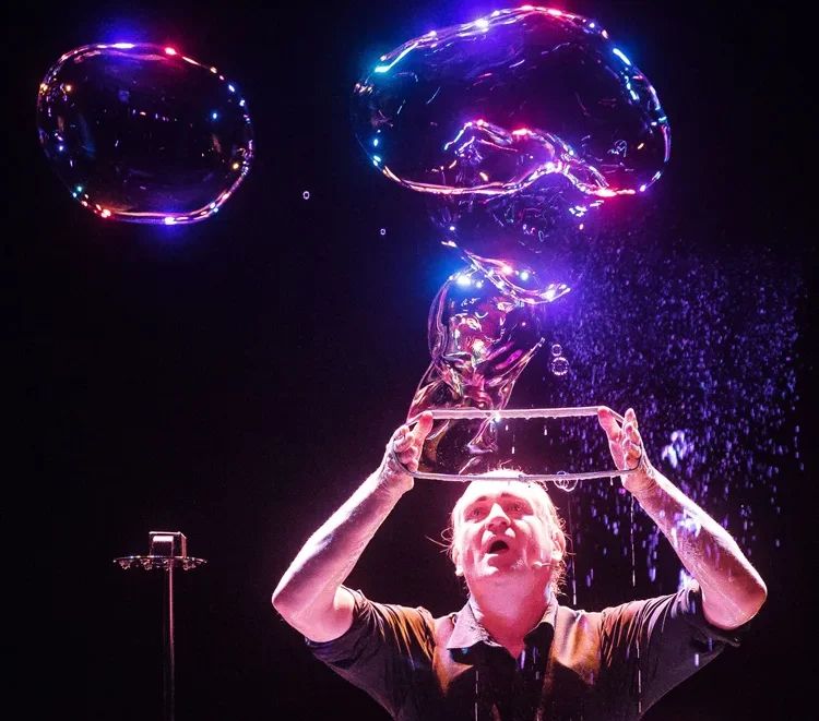 Un artiste de bulles souffle une bulle de savon géante à travers une boucle.